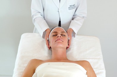 a woman laying on a table with a esthetician standing at her head