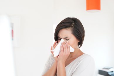 a woman sneezing into a tissue