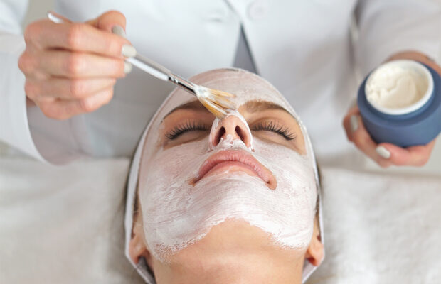 esthetician applying a face mask on a woman's skin