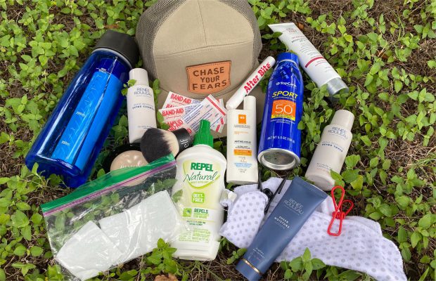 Items for camping skincare routine laid out on grass